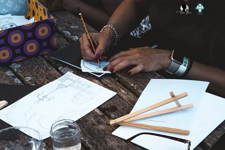 Dettaglio delle mani al lavoro durante il laboratorio Paint & Drink a Calanna